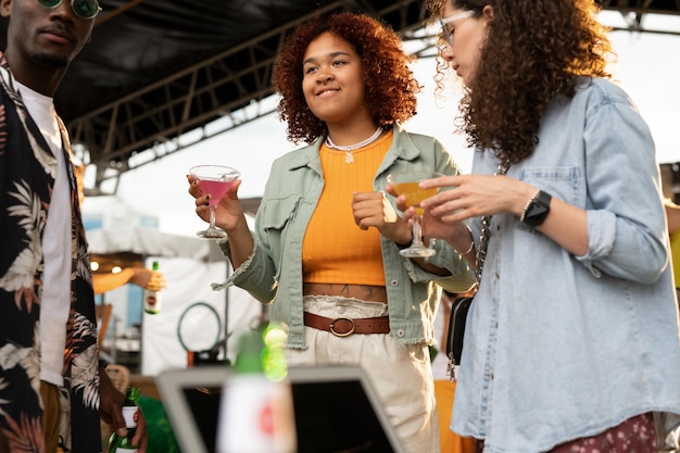 Two intercultural girls with cocktails and african american guy enjoying party