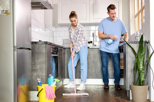 Two Janitors Cleaning Kitchen And Mopping Floor At Home, Caucasian Man And Woman In Casual Weae Enjoy Housekeeping, Cleaning Flat Apartment