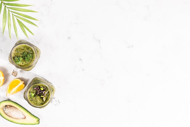 Two jars with a green fruit smoothie on a white background. Healthy eating. top view