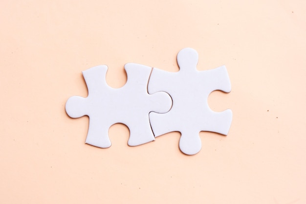 Two jigsaw puzzles pieces on pink background