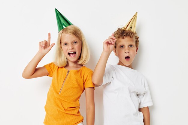 Two joyful children posing emotions holiday colorful caps light background