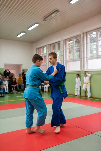 Two judo fighters showing technical skill while practicing martial arts in a fight club The two fit men in uniform fight karate training arts athlete competition conceptSelective Focus