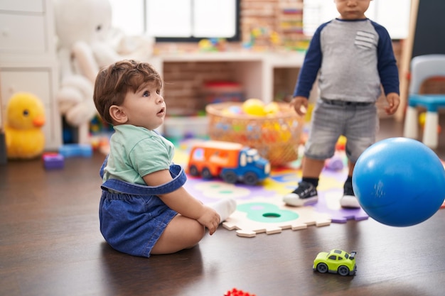 Two kids playing with ball standing at kindergarten