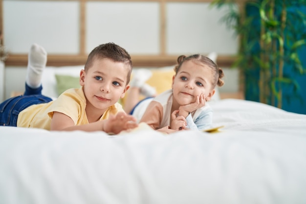 Two kids reading story book lying on bed at bedroom