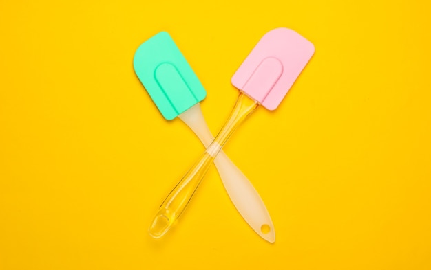 Two kitchen spatula on yellow. Minimalism.