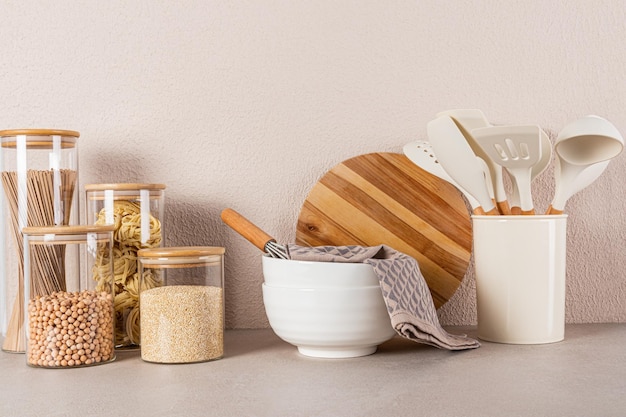 Two large ceramic bowls a set of bulk food jars a set of cooking tools on a stone countertop Beautiful kitchen background Front view Eco cuisine