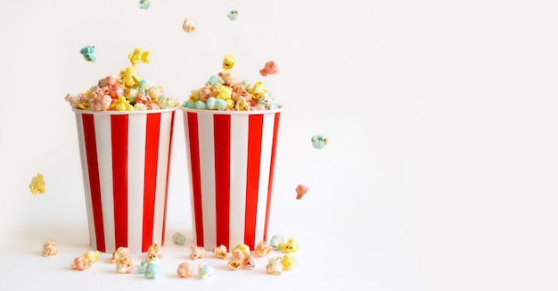 Two large filled glasses with colorful sweet popcorn for fun watching movies in the cinema