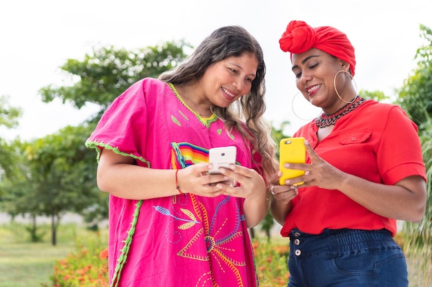 Two Latina women standing in park looking at cell phone and talking