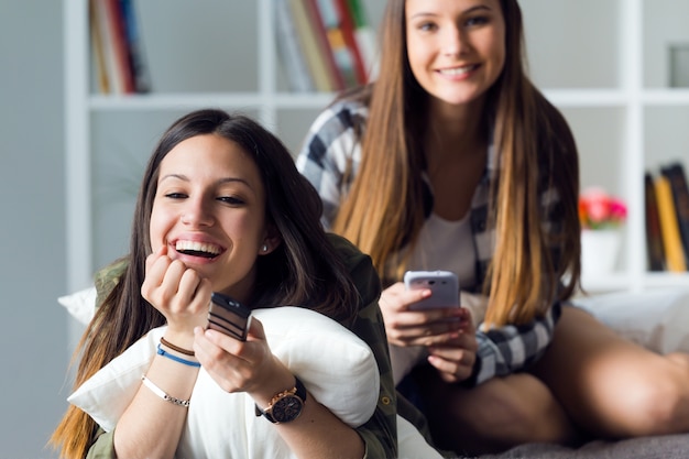 Two laughing girlfriends watching TV