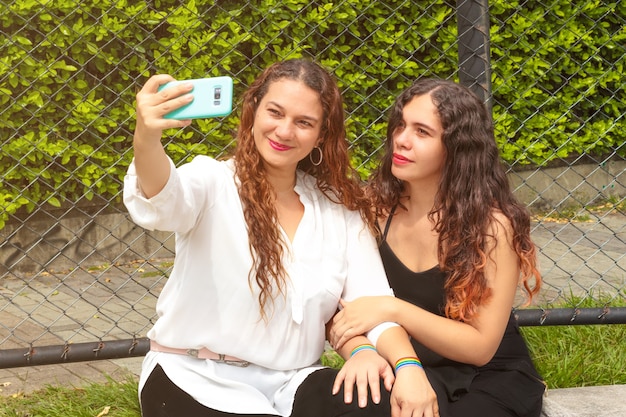 Two lesbian girls taking a picture with the pride flag in their hands