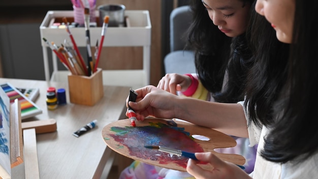 Two little asian girl sitting on couch and painting picture with water color