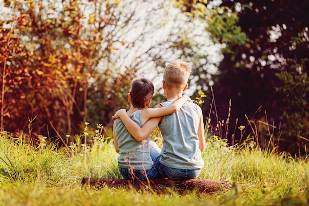 Two little boys friends hug each other in summer sunny day. 