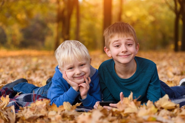 Two little brothers lying in yellow autumn leaves Smiling and having fun Fall day