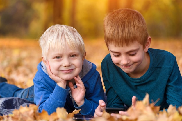 Two little brothers lying in yellow autumn leaves Smiling and having fun Fall day