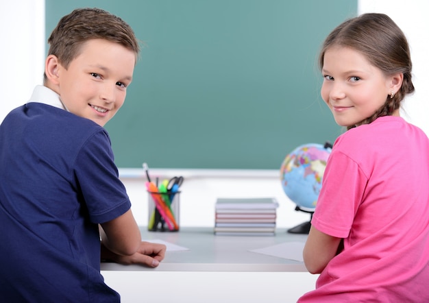 Two little classmates reading a book together