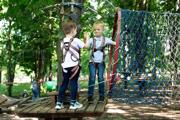 Two little friends say hello while passing the tests in the rope park.