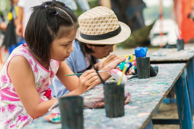 Two little girl painting doll on wood background