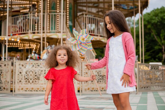 Two little girls in an amusement park playing toy breeze