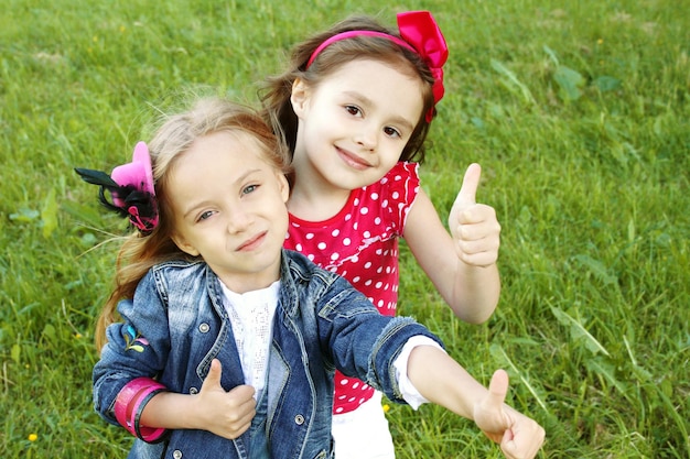 Photo two little girls friends thumbs up