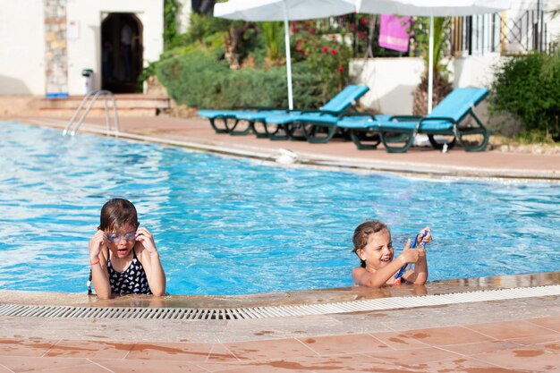 Two little girls in glasses swim in the pool