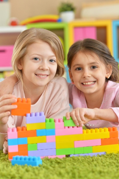 Two little girls playing with colorful plastic blocks