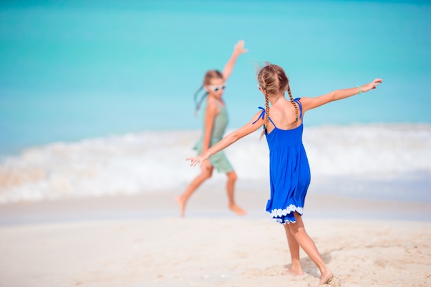 Two little happy girls have a lot of fun at tropical beach playing together