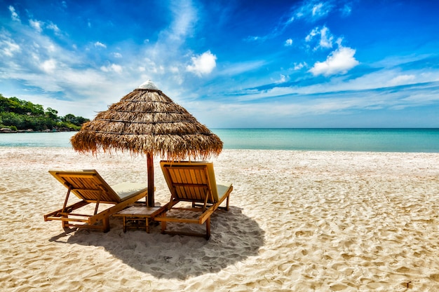 Two lounge chairs under tent on beach