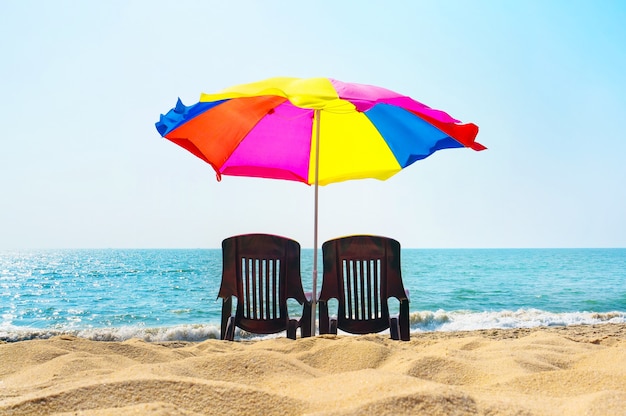 Two lounge chairs under an umbrella on the beach