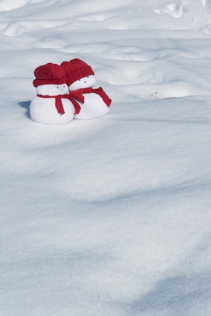 Two lovely snowmen toys on the white snow holiday celebration concept