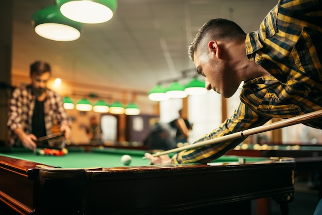 Two male billiard players with cue at the table