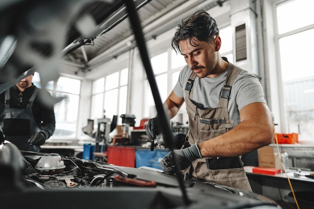 Two male mechanics repairing car in car service