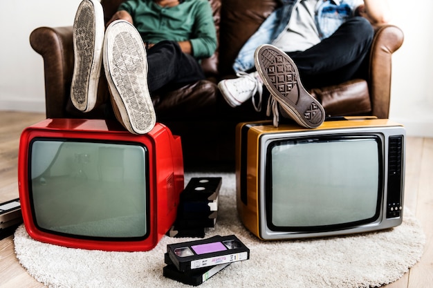 Two man sitting and two retro television