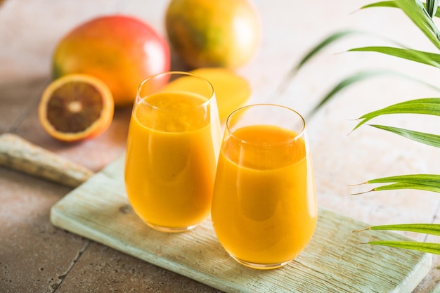 Two mango lassi or kesar milk in glasses Indian healthy ayurvedic cold drink with mango Freshness lassi made of yogurt water spices fruits and ice