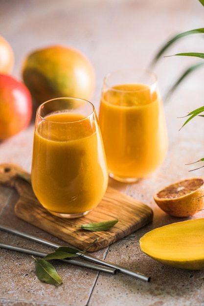 Two mango lassi or kesar milk in glasses Indian healthy ayurvedic cold drink with mango Freshness lassi made of yogurt water spices fruits and ice