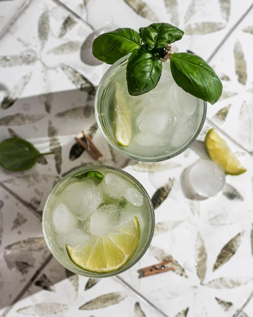 Two margarita cocktails with lime and basil in glasses top view on printed tile