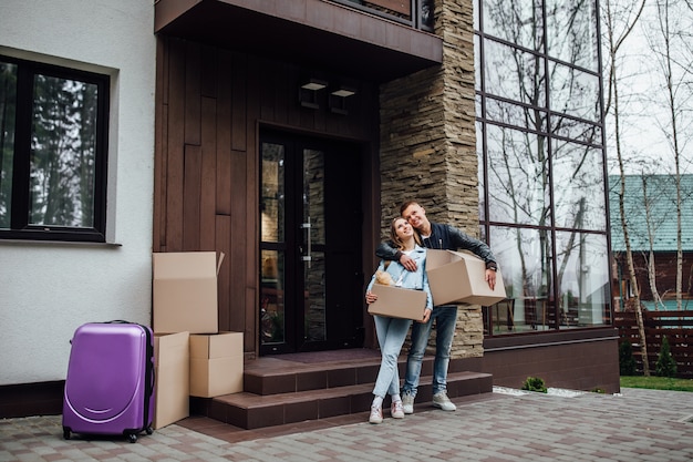 Two married person with unpacking boxes standing near luxury apartaments.