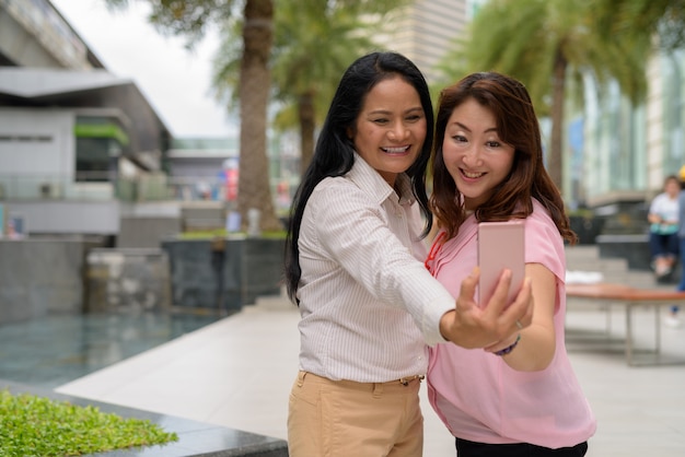 Two mature Asian women together outside the mall in Bangkok city