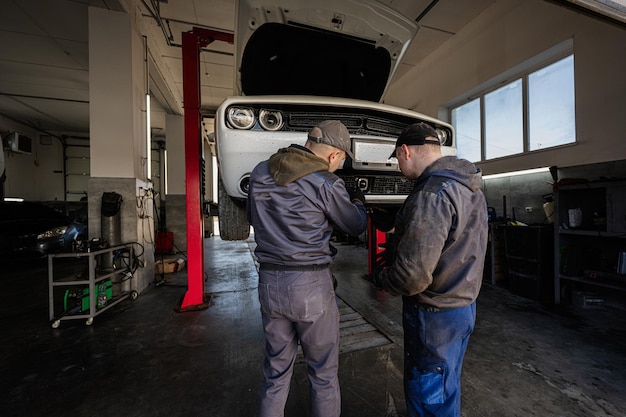 Two mechanic in service repair station calibrate the distronic in muscle car in lift