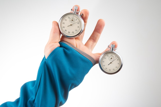 Two mechanical stopwatches hang on the fingers of a male hand Time part precision Measurement of the speed interval