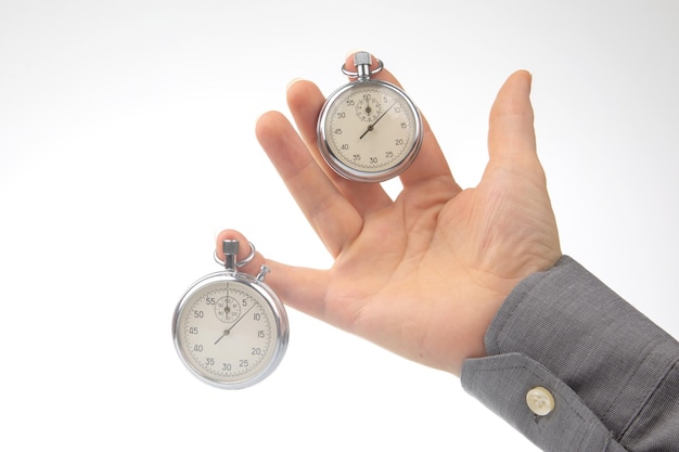 Two mechanical stopwatches hang on the fingers of a male hand Time part precision Measurement of the speed interval