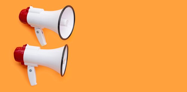 Two megaphones on orange background. Copy space