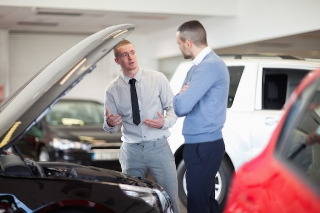 Two men chatting in front of an open engine