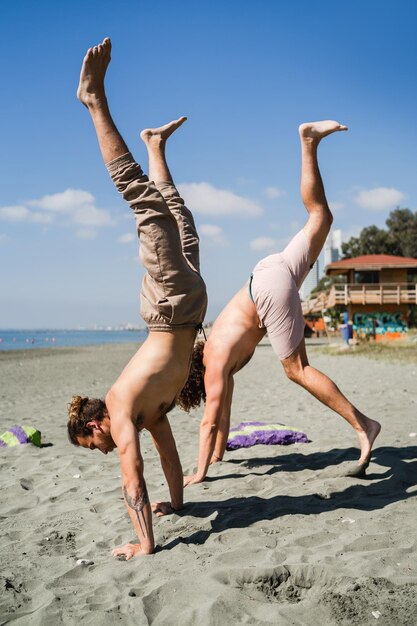 Two men doing handstand for strength and balance on beach