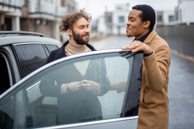 Two men flirting while standing near car on the street