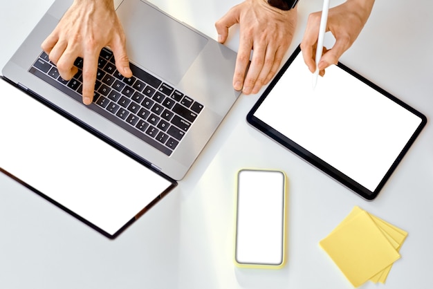 Two men, hands, work on a tablet and laptop with empty, ready to insert, screens. High quality photo