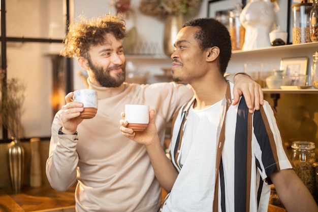 Two men talking and drinking coffee on kitchen at home