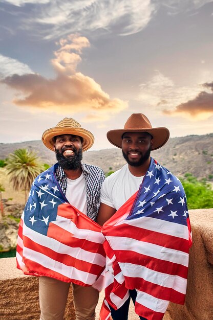 two men wearing american flags pose for a photo in front of a mountain