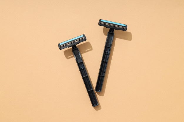 Photo two mens black disposable razors on beige background top view