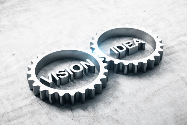 Two metal cog gears with text vision and idea on concrete table