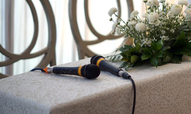 Photo two microphones and flowers on a table for wedding procession